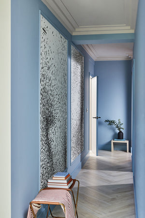 Powder blue narrow hallway showing panels of Disorder in Stasis wallpaper in black and white