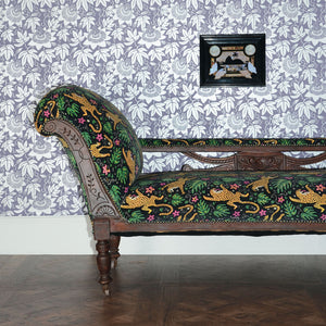 Reupholstered chaise lounge in black leopard print velvet with arts and crafts style wallpaper